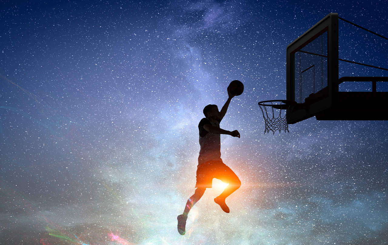 A silhouette of person jumping in the air shooting a basketball.