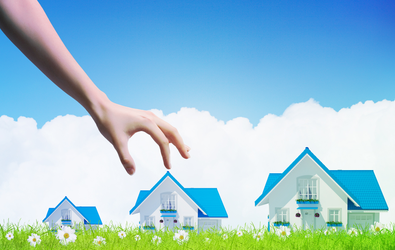 Three houses, small, medium and large, with hand coming from the clouds picking the medium.