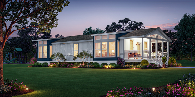 A manufactured new home in an open green setting at dusk with the lights on inside the home. 