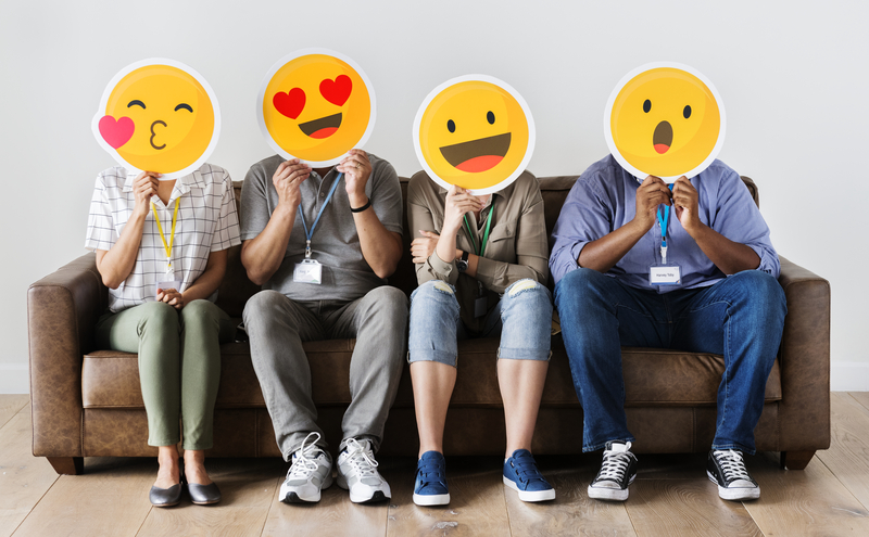 People sitting down with emoticons over their faces.
