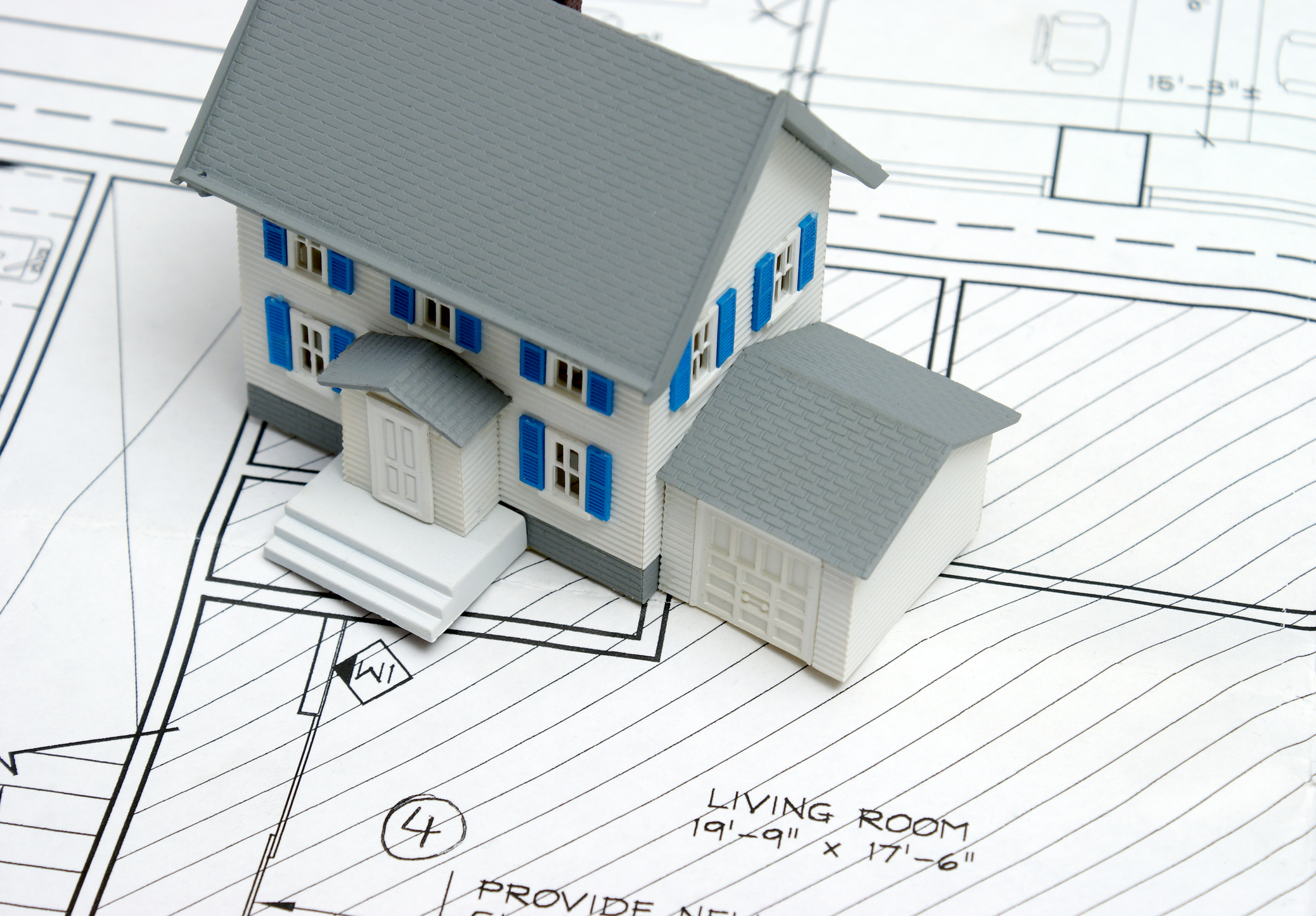 Little gray, blue, and white toy house on top of black and white floor plans.